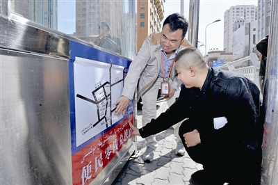 4月20日11时,乌鲁木齐市新市路南社区的工作人员正在新疆人民医院公交站岗亭张贴换零钱的便民提示。